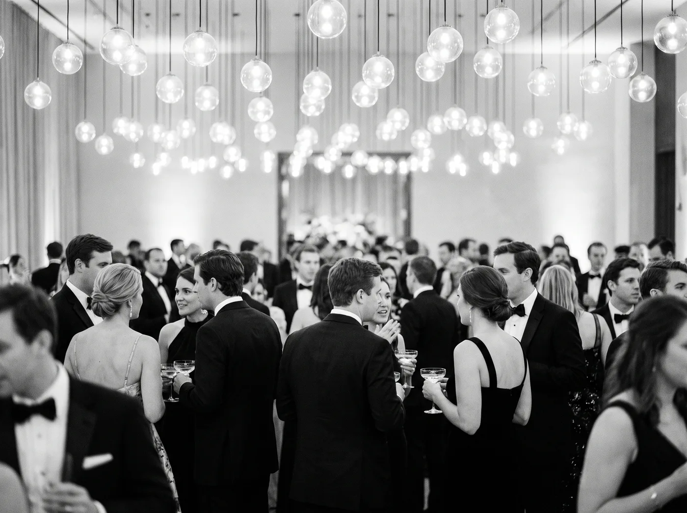 A crowded evening cocktail reception under glass globe lights