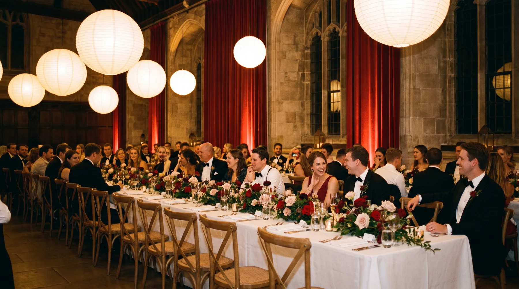 A long banquet wedding table set beneath white paper lanterns